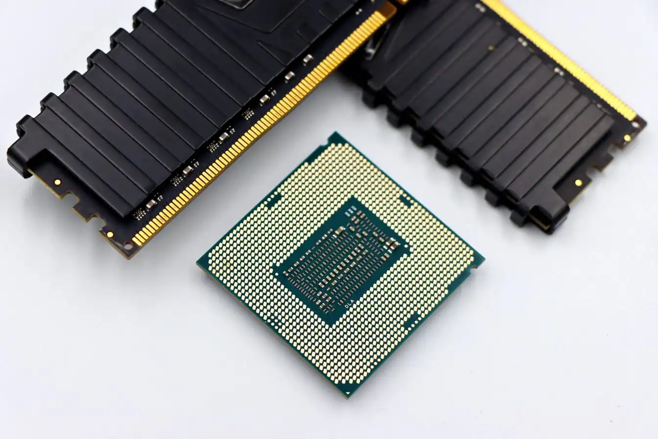 A processor and two memory modules lying on a plain white surface, photographed close up.
