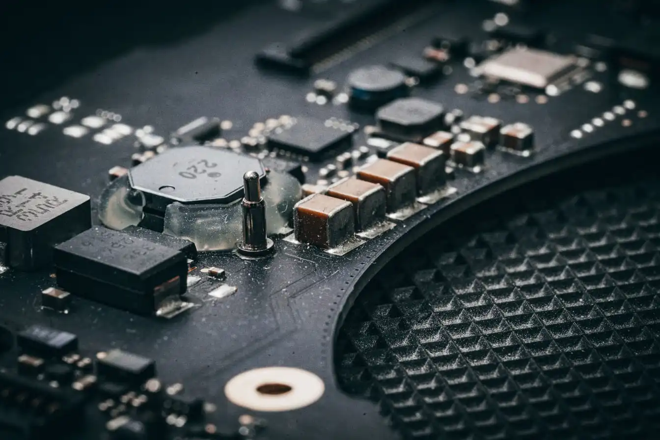 Close-up of a green printed circuit board, with surface-mounted chips, capacitors and solder joints filling the frame.