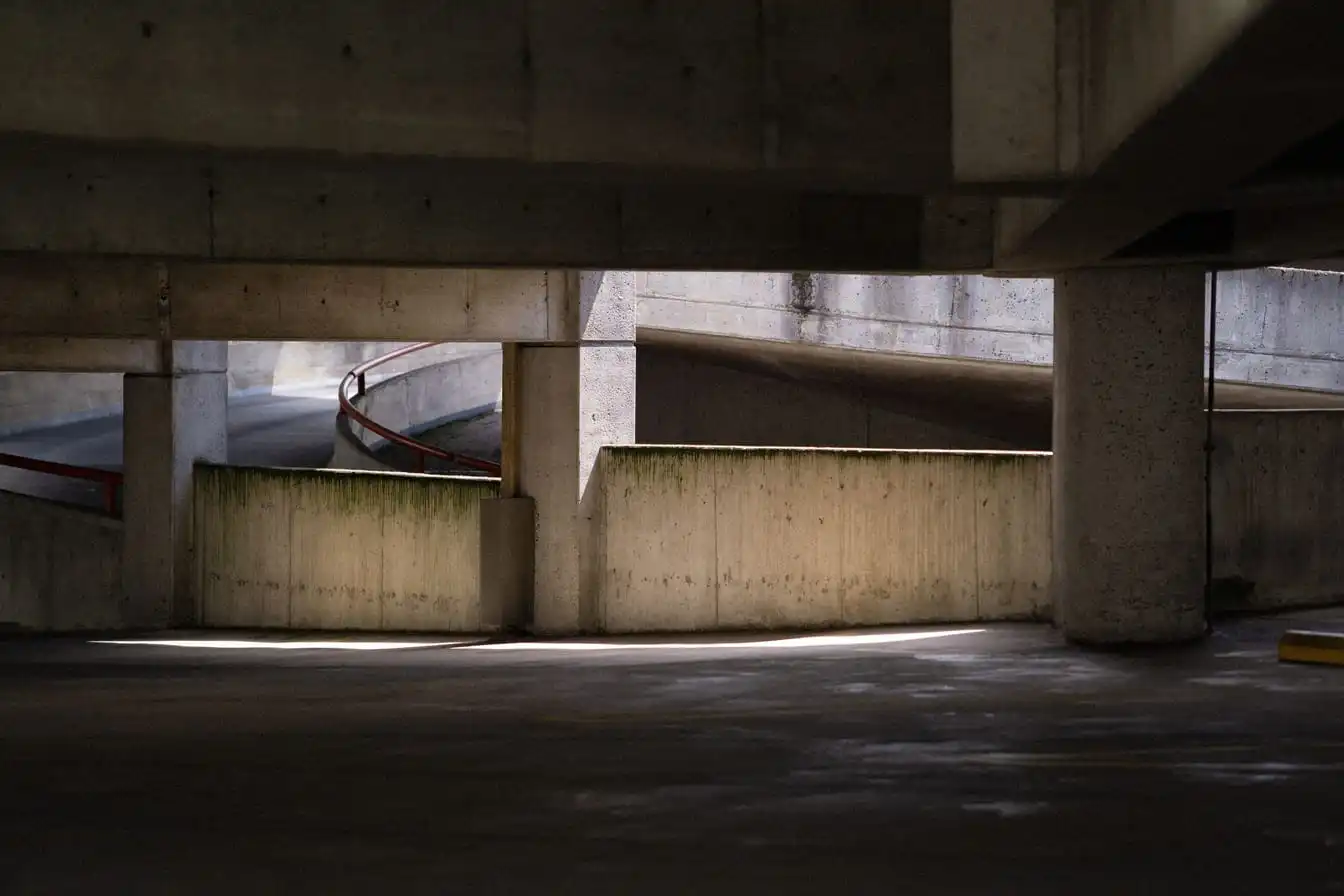 Concrete parking garage with spiral ramp and lighting effects creating shadows.